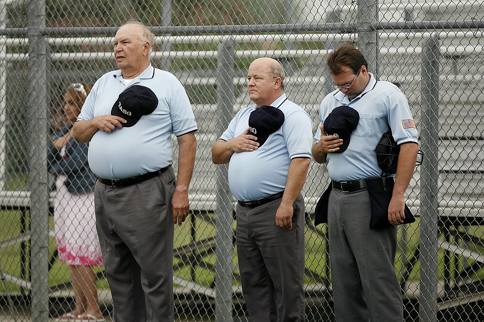 Men holding their hats unto their chest