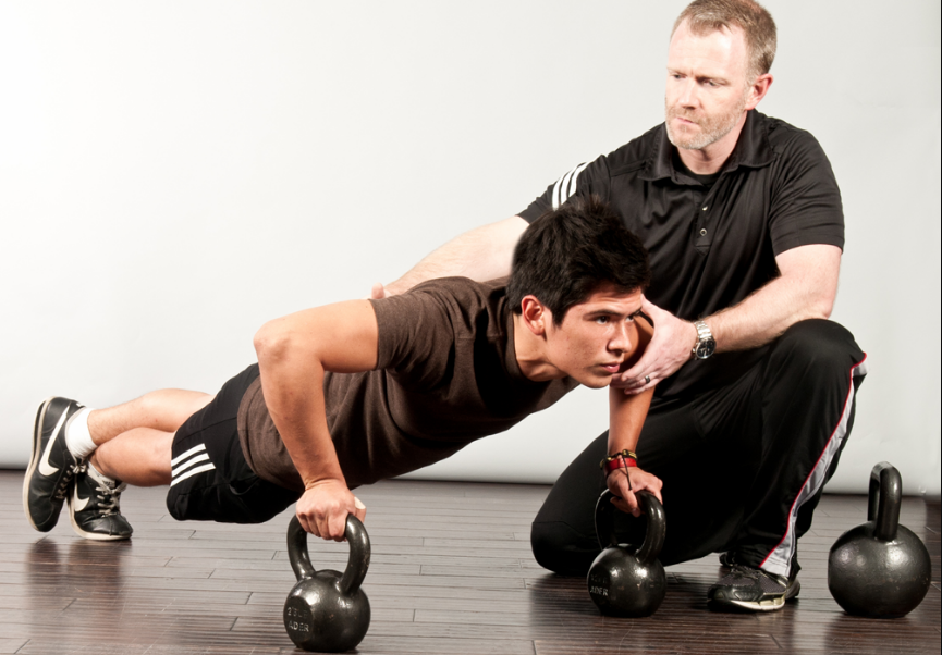 Man doing push ups assisted by his trainer