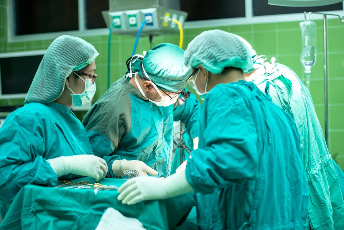 4 people wearing lab gown in an operating room